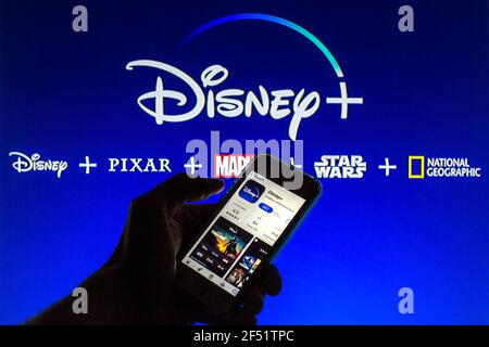 In questa illustrazione fotografica l'app Disney+ visualizzata sullo schermo di uno smartphone in App Store con il logo Disney+ sullo sfondo. Foto Stock