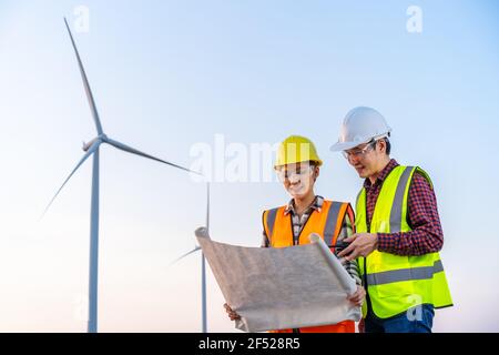 il team di giovani ingegneri analizza un disegno di progetto della turbina eolica fattoria Foto Stock