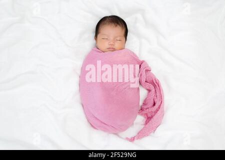 il bambino neonato dorme in coperta di tessuto rosa su un letto Foto Stock