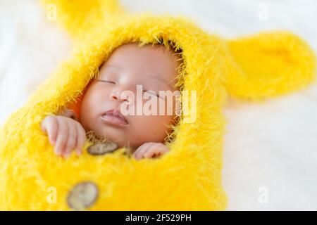 neonato in tuta da pelo bunny che dorme su un letto Foto Stock