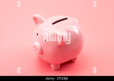 Prosperità nelle finanze personali, crescita del denaro, economia moderna e capitale di risparmio tema concettuale con una piggy banca isolata su sfondo rosa Foto Stock
