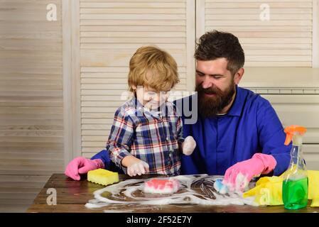 Padre sta insegnando a un figlio una pulizia. Buona famiglia pulisce la camera. Papà e bambina sono spolverati, lavando il pavimento e spray. Foto Stock