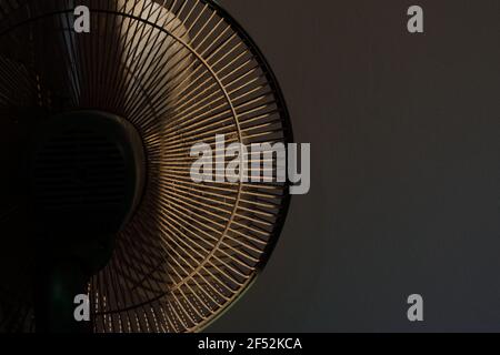 Chiusura della parte posteriore della ventola elettrica piena di polvere in piedi nella stanza contro muro di cemento Foto Stock