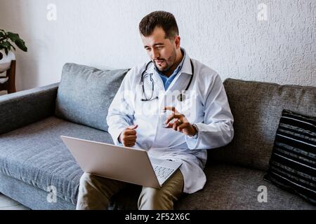 latino medico uomo che consulta in linea e che lavora con il calcolatore a. casa a Città del Messico Foto Stock