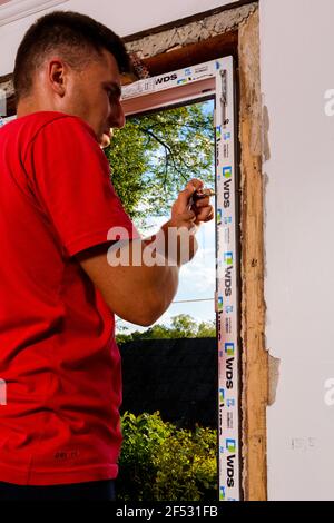 Dolyna, Ucraina 31 luglio 2020: Un dipendente installa un telaio per finestre, installando una finestra in plastica. Novità Foto Stock