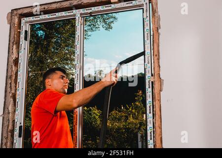 Dolyna, Ucraina 31 luglio 2020: Un dipendente installa un telaio per finestre, installando una finestra in plastica. Novità Foto Stock