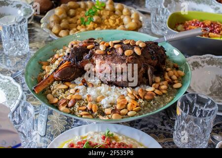 Coscia di agnello alla griglia, su grano duro o fregiolo o riso e noci vista dall'alto su un tavolo da pranzo. Foto Stock