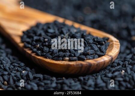 Semi di Nigella sativa, primi piani fotografici, con cucchiaio di legno, fuoco selettivo. Foto Stock