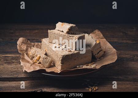 Pezzi di alva con arachidi sono cosparsi di semi su uno sfondo marrone scuro. Vista laterale. Concetto di dessert. Foto Stock
