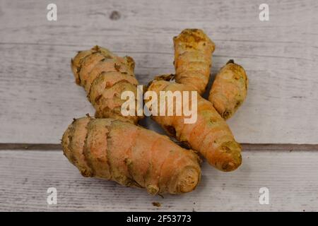 Primo piano di fette e radice curcica intera o rizoma. Native del subcontinente indiano, le radici sono usate in cucina & medicina ayurvedica. Foto Stock