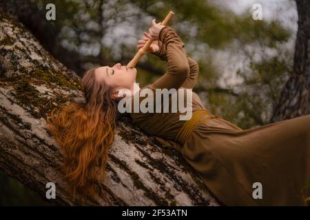 Donna rossa in abito che cammina in fantasy fiaba foresta Foto Stock