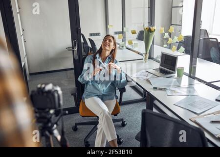 Donna designer che viene filmata con la fotocamera nel suo ufficio Foto Stock