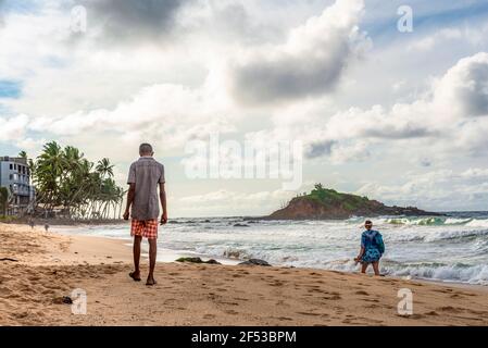 Residenti locali e turisti a piedi lungo la costa indiana dell'oceano Sull'isola di Sri Lanka Foto Stock