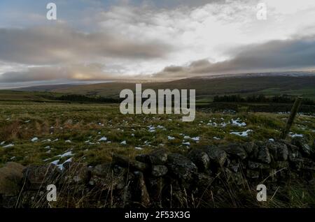 Un muro di pietra a secco con colline innevate oltre a Weardale, North Pennines, County Durham, Regno Unito Foto Stock