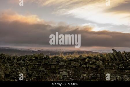 Un muro di pietra a secco con colline innevate oltre a Weardale, North Pennines, County Durham, Regno Unito Foto Stock