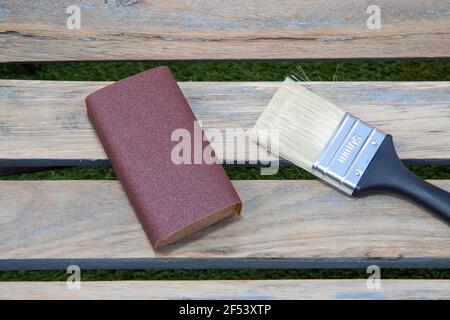 Un blocco di levigatura e una spazzola di vernice su un banco di legno pronto per levigare, il concetto domestico di lavorazione del legno di miglioramento Foto Stock