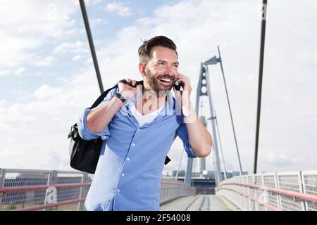 Ritratto di uomo maturo all'aperto con borsa che parla su cellulare telefono e ridendo Foto Stock