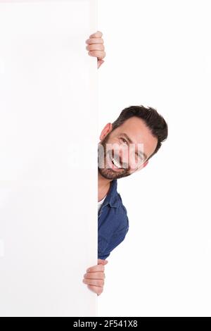 Ritratto di un uomo maturo sorridente che oscura sopra un cartello vuoto su sfondo bianco Foto Stock