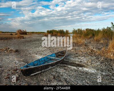 Vecchia barca da pesca in legno su un lago asciutto. Paesaggio autunnale. Tradizionale barca di legno fatta in casa con fondo piatto Foto Stock