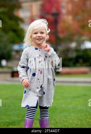 ritratto di una bambina che si fooling e che cammina intorno dentro una città Foto Stock