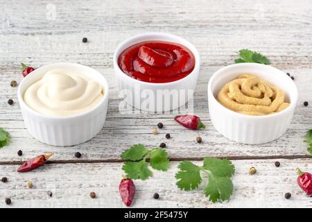 Set di varie salse con spezie su fondo di legno bianco. Maionese ketchup senape. Vista dall'alto Foto Stock