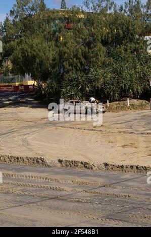 Gold Coast Australia. Soleggiato dopo una tempesta che causa danni lungo la costa. Uomini che ispezionano auto distrutte nel parcheggio sulla spiaggia. Foto Stock