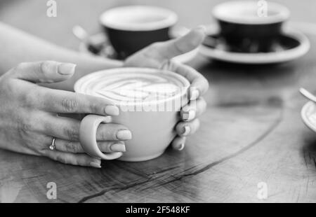 Tazza di caffè a forma di cuore. Buon caffè del mattino. Barista serve caffè. Vibrazioni del mattino al caffè. Cuore latte art. Donna tenere calda tazza di caffè con Foto Stock