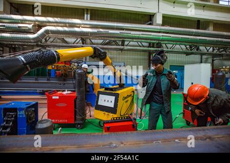 Ekibastuz,Pavlodar,Kazakhstan-maggio 28,2012:Car-building plant.gas-bruciatore saldatura di parti di carro.Yellow aspiratore di fumi (macchina di aspirazione aria)e lavoratori. Foto Stock