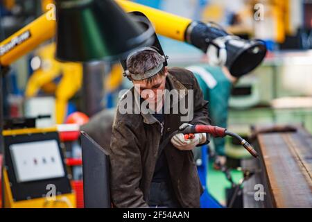 Ekibastuz, regione di Pavlodar, Kazakistan - Maggio 28 2012: Impianto ferroviario per la costruzione di automobili. Saldatura con bruciatore a gas di parti di carro. Giovane saldatore in maschera protettiva. Foto Stock