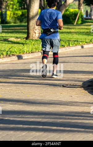 Runner sportivo che indossa le ginocchiere mentre si fa jogging all'aperto Foto Stock
