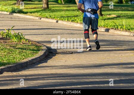 Sportivo con ginocchiere e jogging nel parco Foto Stock