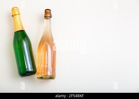 Bottiglia di vino frizzante rosa e spumante bianco in bottiglia verde. Composizione del vino minimalista vista dall'alto su sfondo bianco. Due bottiglie di sidro Foto Stock