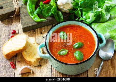 Il concetto di cibo sano e dietetico, piatto vegetariano. Zuppa di pomodoro o zuppa di gazpacho con crostini su un tavolo rustico in legno. Foto Stock