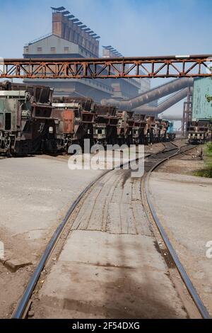 Impianto di metallurgia edilizia industriale. Scorie auto in pista. Rotaie in primo piano. Cielo blu e impianto metallurgico principale edificio sullo sfondo. Foto Stock