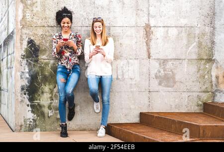 Felici le ragazze i migliori amici che si divertono all'aria aperta con mobile smart Telefono - concetto di amicizia con le girlfriends milleniali sugli smartphone Foto Stock