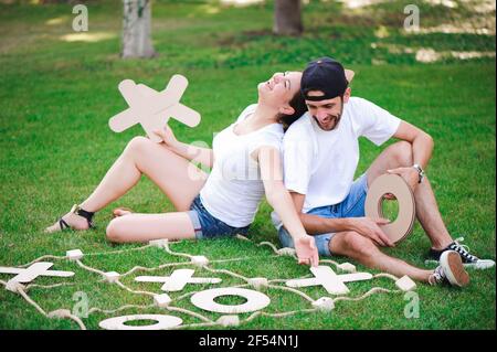 Ridere un ragazzo e una ragazza gioca tic-tac-toe nel parco. Foto Stock