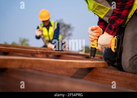 Primo piano tetto lavori su struttura tetto di costruzione in cantiere, Roofer con pistola ad aria o pneumatica per chiodi e installazione su struttura tetto in legno Foto Stock