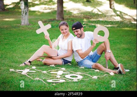 Ridere un ragazzo e una ragazza gioca tic-tac-toe nel parco. Foto Stock