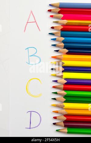 Imparare i colori e le lettere con matite colorate su carta bianca. Foto Stock