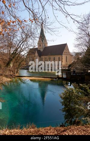 Immagine verticale di una bella chiesa vicino al lago riflettente A Blaubeuren Germania Foto Stock