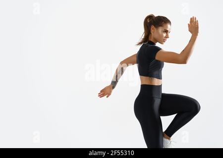 Determinato allenamento muscolare femminile atleta, alzando le gambe e facendo esercizi di stretching. Donna sportiva in allenamento sportivo in interni, facendo fitness Foto Stock