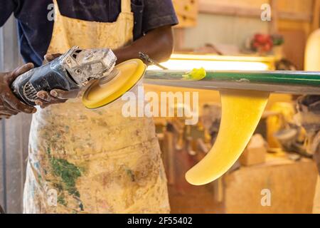 Primo piano di un artigiano africano tavola da surf Shaper lavorare in un'officina di riparazione Foto Stock