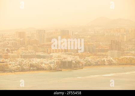 Las Palmas, Gran Canaria, Isole Canarie, Spagna. 24 Marzo 2021. Vista su Las Palmas e sulla spiaggia della città. Senza data per la ripresa delle vacanze straniere per i vacanzieri britannici, i locali e i turisti dispari hanno la spiaggia della città a se stessi a Las Palmas su Gran Canaria come caldo e polveroso vento Calima soffiare dal Sahara, riducendo la visibilità e la qualità dell'aria. Credit: Alan Dawson/Alamy Live News. Foto Stock