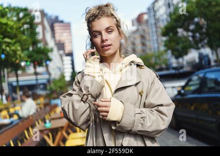 Donna giovane ed elegante che cammina lungo la strada e parla al telefono, la mattina si porta in ufficio. Donna d'affari che chiama il cliente sul suo modo di lavorare Foto Stock