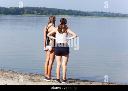 Due ragazze adolescenti sul laghetto della riva, vista posteriore Foto Stock