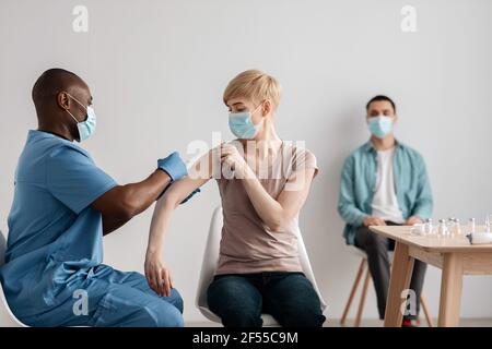 Il paziente viene vaccinato contro il virus corona riceve iniezione intramuscolare a. visita al medico in clinica Foto Stock