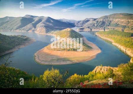 Paesaggio con un meandro di un fiume sullo sfondo di montagne e cielo blu con nuvole bianche Foto Stock