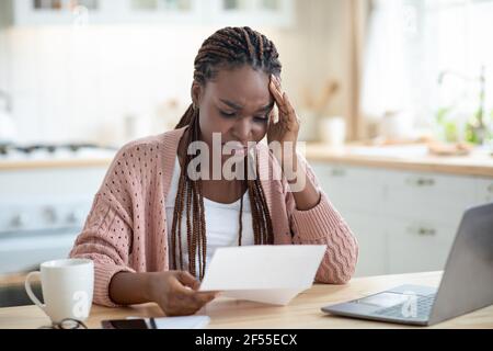 African American Female Freelancer avendo stress mentre lavora con i documenti A casa Foto Stock