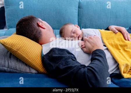 Padre che dorme con il bambino sul divano a casa Foto Stock