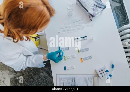 Femmina medico generico che fa il campione medico test diagnostico rapido a. sala esame Foto Stock